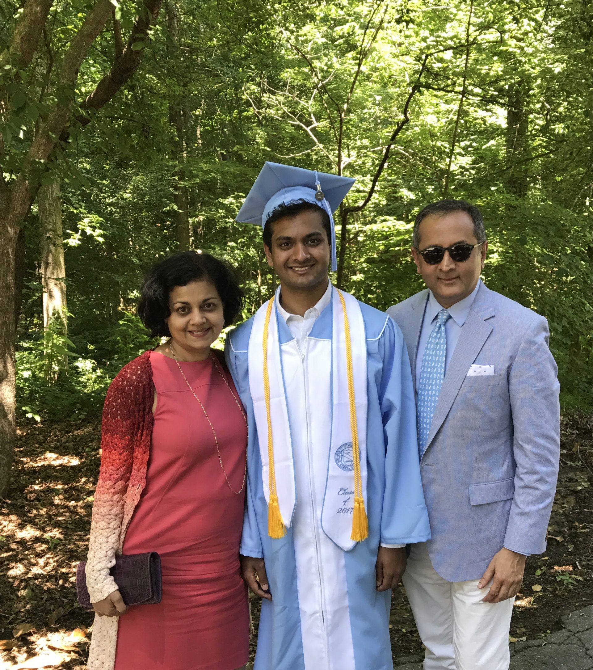 Raj and Mary Rajkumar with their son who is wearing a graduation cap and gown.